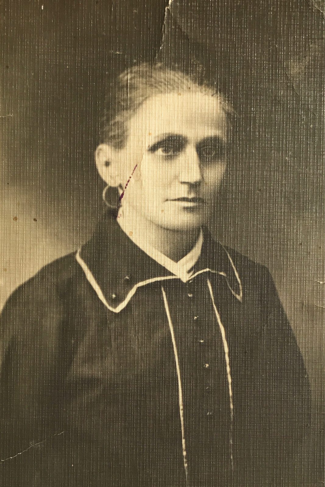 Sepia studio portrait of a woman in a dark blouse with a pale piped collar and a hoop
             earring, hair drawn back